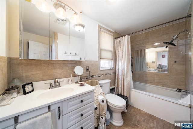 full bath with visible vents, tile walls, toilet, shower / bath combo with shower curtain, and vanity