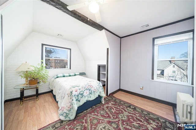 bedroom with radiator, a ceiling fan, wood finished floors, visible vents, and lofted ceiling