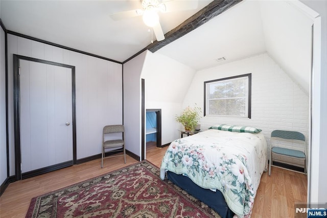 bedroom featuring visible vents, wood finished floors, a ceiling fan, and vaulted ceiling