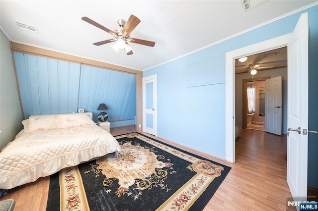 bedroom with visible vents, crown molding, ceiling fan, and wood finished floors