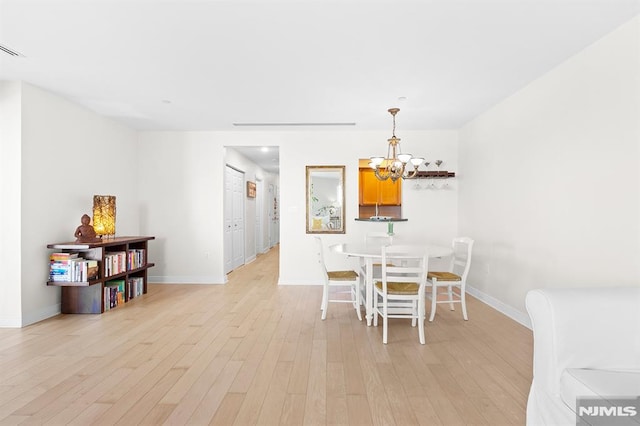 dining area featuring an inviting chandelier, baseboards, and light wood-style floors