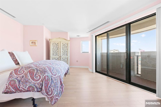 bedroom with baseboards, wood finished floors, and access to outside