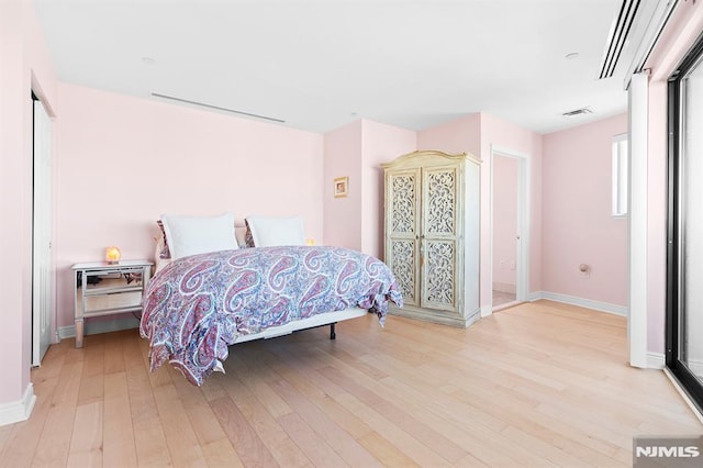 bedroom with visible vents, light wood-type flooring, and baseboards