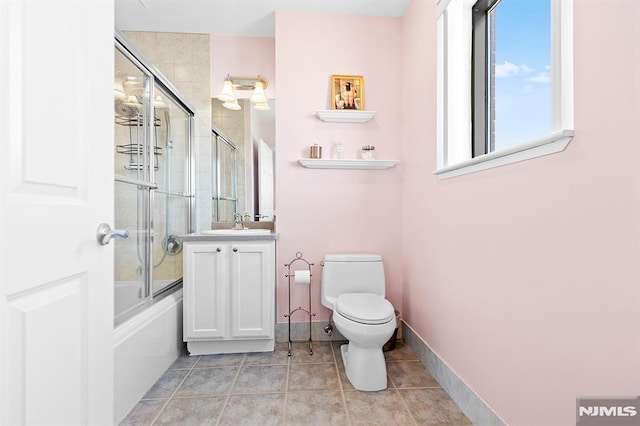 bathroom featuring tile patterned floors, toilet, baseboards, bath / shower combo with glass door, and vanity