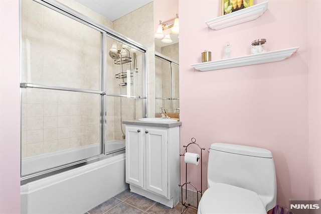 full bath featuring tile patterned floors, combined bath / shower with glass door, toilet, and vanity