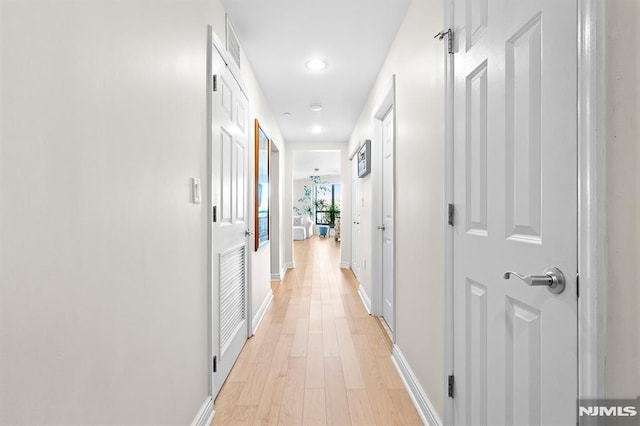 hall featuring light wood-style flooring and baseboards