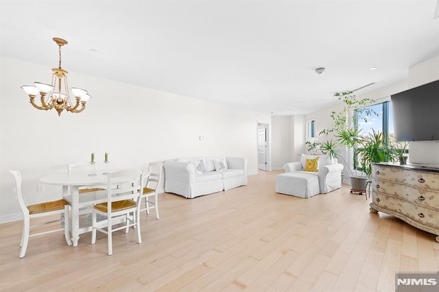 living area featuring light wood-style flooring, baseboards, and a chandelier