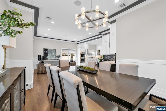 dining room with visible vents, wainscoting, dark wood-type flooring, crown molding, and a notable chandelier