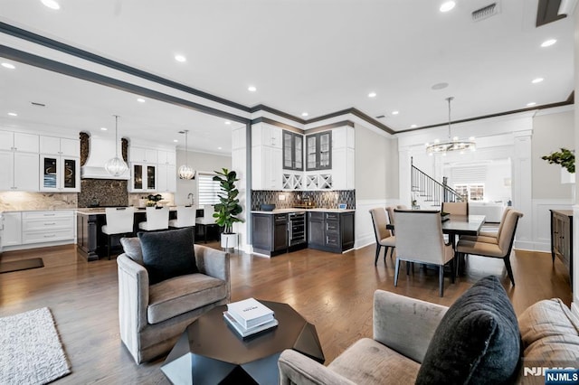 living room featuring beverage cooler, visible vents, indoor bar, dark wood-type flooring, and a notable chandelier