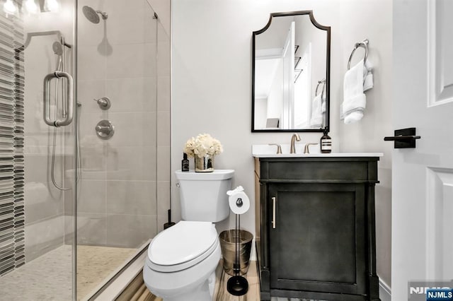 bathroom featuring vanity, a shower stall, and toilet