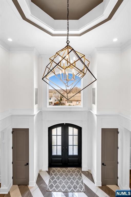 foyer entrance featuring plenty of natural light, a tray ceiling, crown molding, and french doors