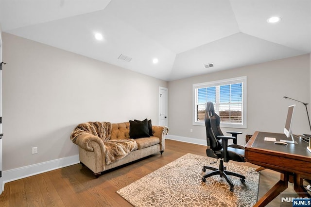 home office featuring visible vents, vaulted ceiling, baseboards, and wood finished floors