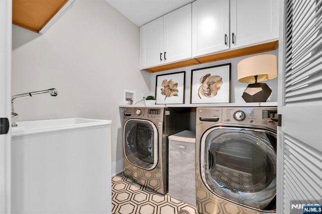 clothes washing area featuring washing machine and dryer and cabinet space