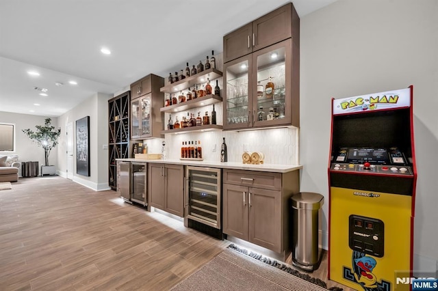 bar featuring light wood-style flooring, recessed lighting, beverage cooler, backsplash, and wet bar