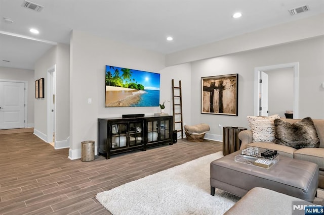 living area with recessed lighting, visible vents, and wood finished floors