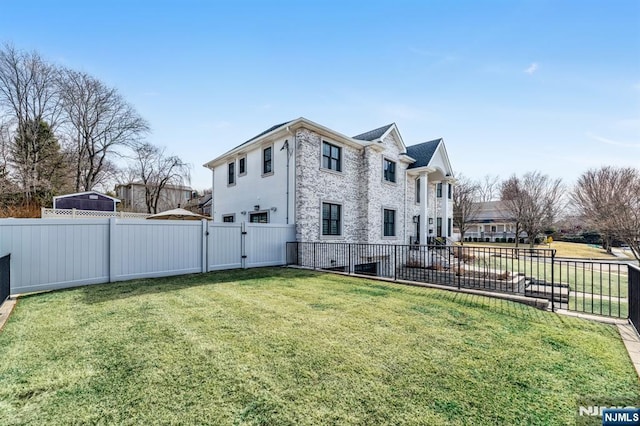 view of side of home featuring a fenced backyard, a gate, and a lawn