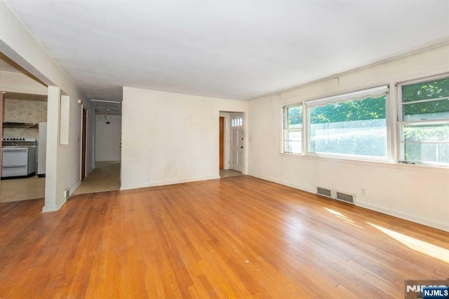 unfurnished living room featuring wood finished floors, visible vents, and baseboards