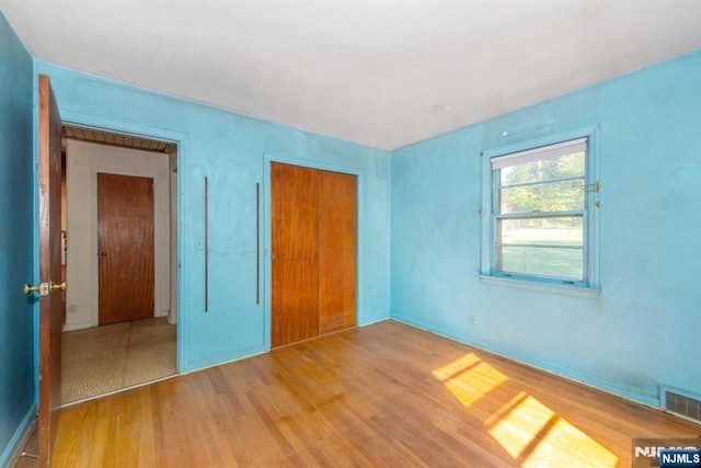 unfurnished bedroom with a closet, visible vents, and wood finished floors