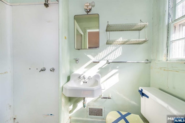 half bathroom with toilet, a sink, and visible vents