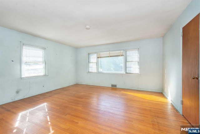 empty room with light wood-style floors and visible vents