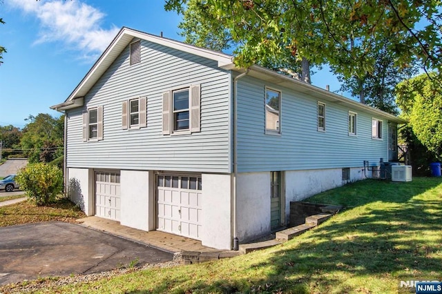 view of side of property with central AC, a lawn, and an attached garage