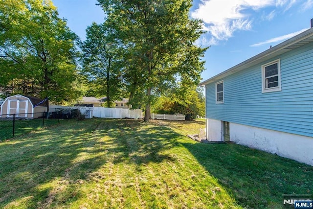 view of yard featuring a storage shed, a fenced backyard, and an outbuilding