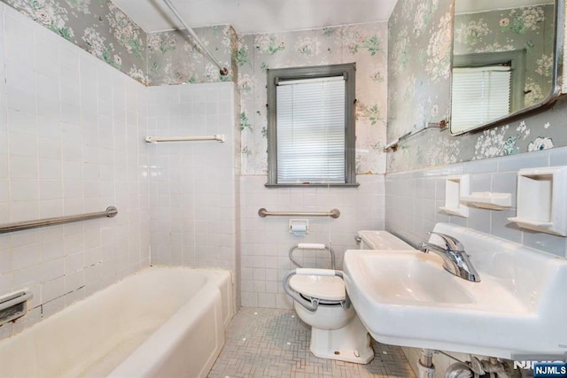 bathroom featuring tile walls, toilet, wainscoting, tile patterned flooring, and wallpapered walls