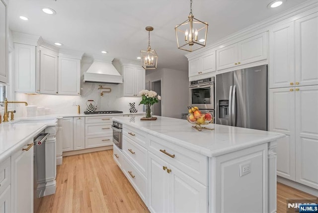 kitchen featuring white cabinets, light wood-style flooring, custom range hood, a kitchen island, and stainless steel appliances