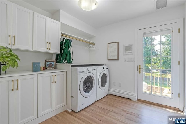 clothes washing area with light wood-type flooring, cabinet space, visible vents, and washing machine and clothes dryer