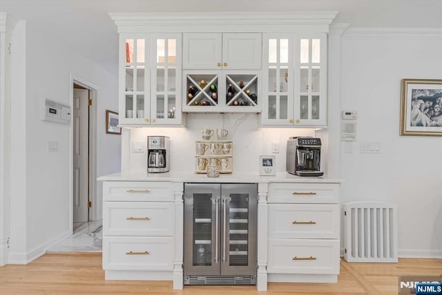 bar with a bar, beverage cooler, baseboards, and decorative backsplash