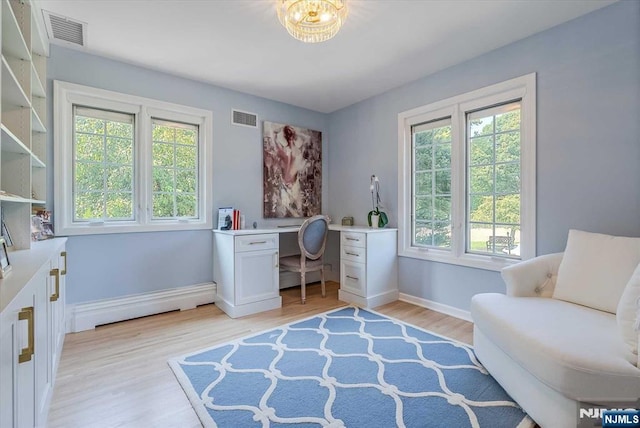 office space featuring a baseboard heating unit, light wood-style flooring, visible vents, and baseboards