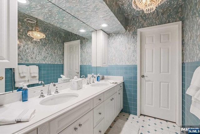 bathroom with wallpapered walls, tile walls, and a sink