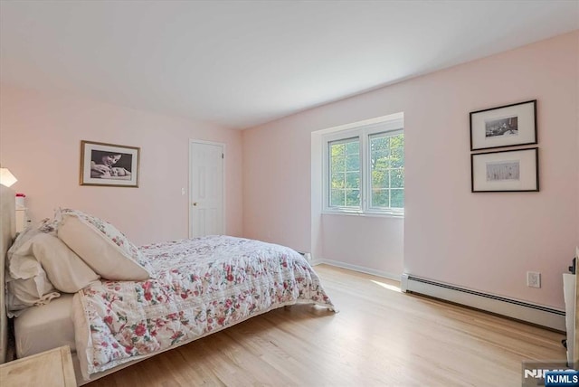 bedroom with baseboards, baseboard heating, and wood finished floors