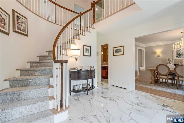 staircase featuring a high ceiling, baseboards, marble finish floor, an inviting chandelier, and crown molding