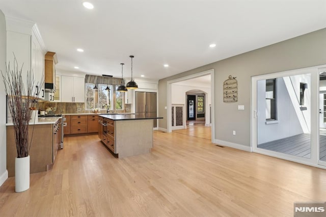 kitchen featuring a center island, recessed lighting, light wood-style flooring, arched walkways, and stainless steel appliances