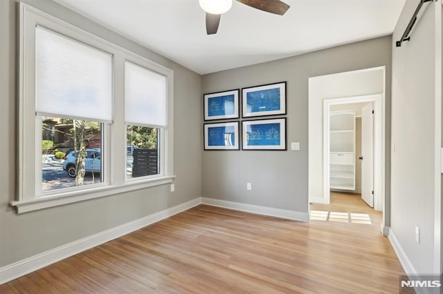 spare room featuring a ceiling fan, light wood-type flooring, and baseboards