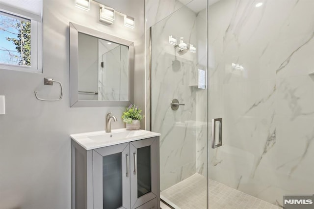 full bathroom featuring vanity and a marble finish shower