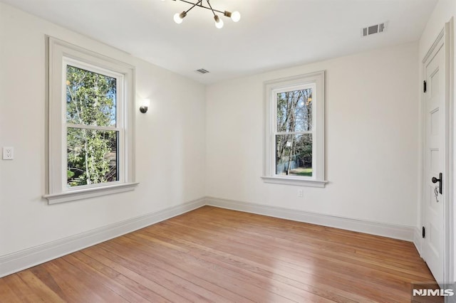 spare room featuring visible vents, baseboards, and light wood finished floors