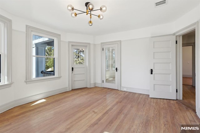 foyer entrance with a notable chandelier, visible vents, light wood-type flooring, and baseboards