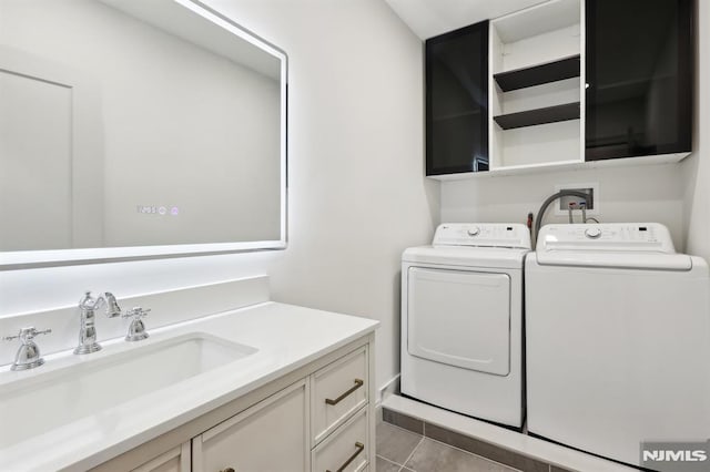 clothes washing area featuring cabinet space, independent washer and dryer, tile patterned floors, and a sink