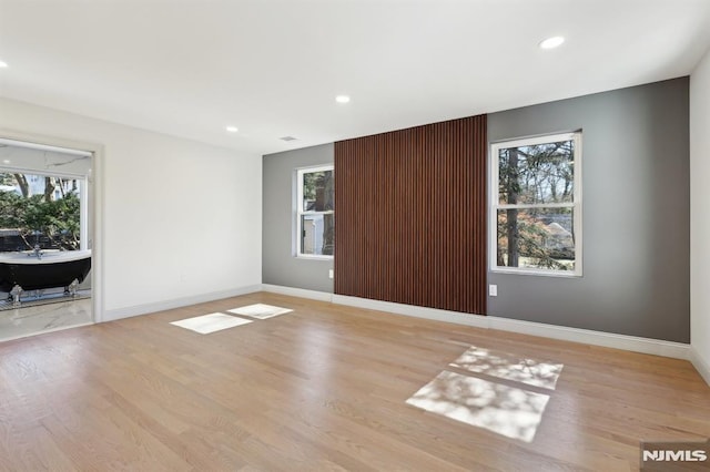 unfurnished room with plenty of natural light, baseboards, and wood finished floors