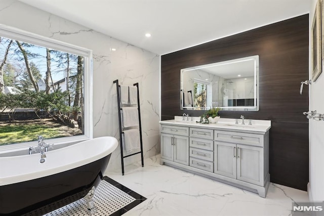 full bath with a sink, marble finish floor, and a wealth of natural light