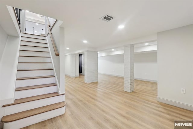 finished basement with visible vents, baseboards, stairway, recessed lighting, and wood finished floors