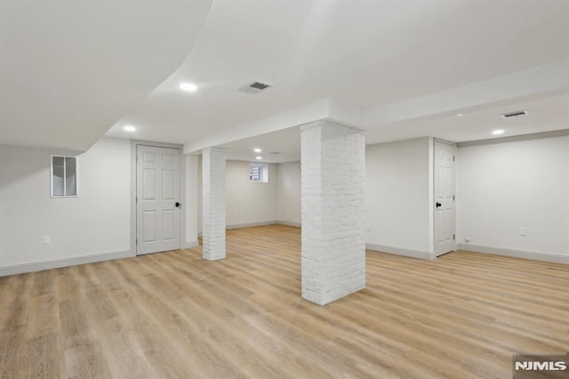 finished below grade area featuring light wood-style floors, visible vents, and baseboards