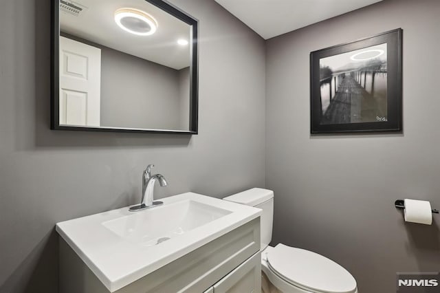 bathroom with vanity, toilet, and visible vents