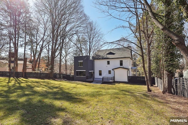 rear view of property with a lawn, a fenced backyard, and stucco siding