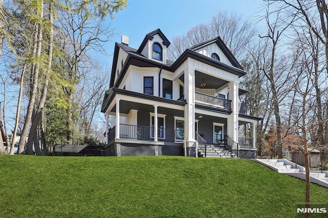 view of front of house featuring a front lawn, board and batten siding, covered porch, a balcony, and a chimney