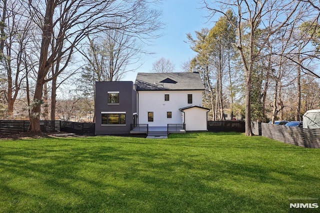 back of property with stucco siding, a lawn, and fence