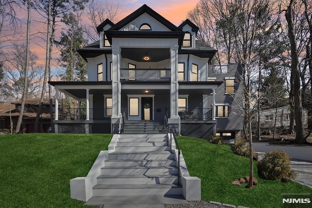 view of front of house featuring a yard, a balcony, and covered porch