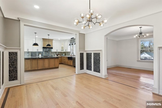 kitchen featuring tasteful backsplash, open floor plan, light wood-type flooring, hanging light fixtures, and brown cabinetry